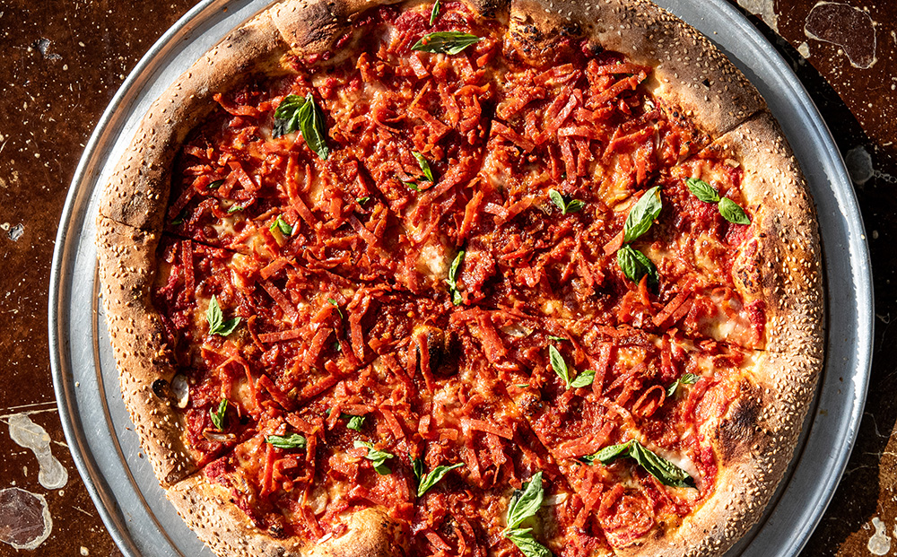 Overhead shot of pizza with innovative ribbon pepperoni and basil