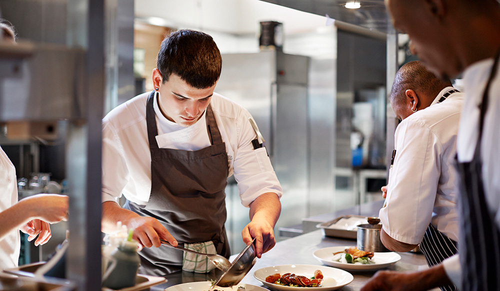 Restaurant staff preparing dishes in back of house