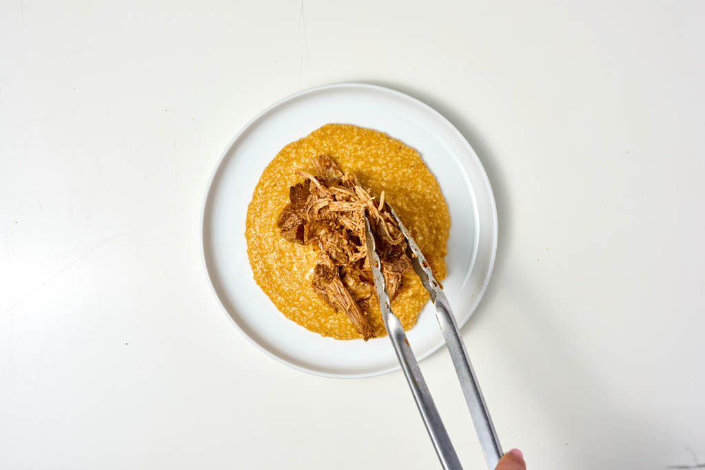 Placing the barbacoa on top of the grits