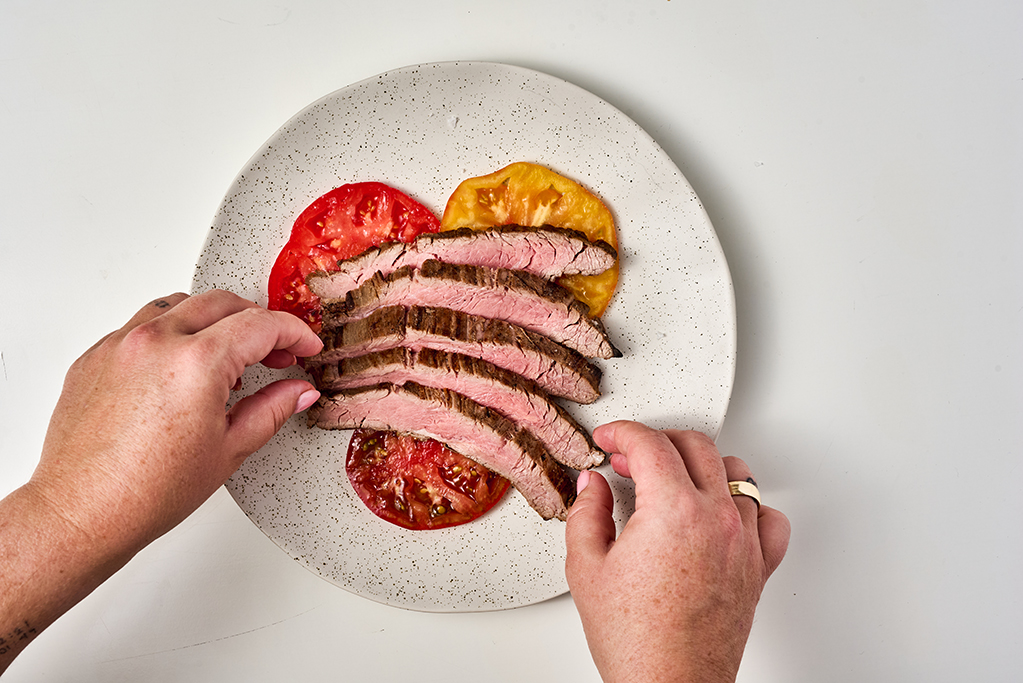 Plating steak slices on top of tomato slices